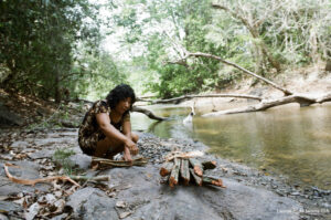 Mulher Arara acende uma fogueira na margem de um igarapé. Foto: Leonardo Halszuk/Isa